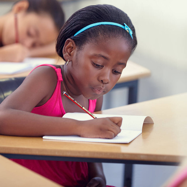 Учиться чему-то новому каждый день. симпатичная маленькая девочка, делающая свою работу в классе - Фото, изображение