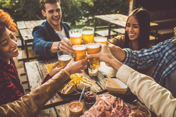 Familia multiétnica divirtiéndose en la cena del patio trasero. Jóvenes disfrutando del tiempo juntos en un pub al aire libre - Foto, imagen