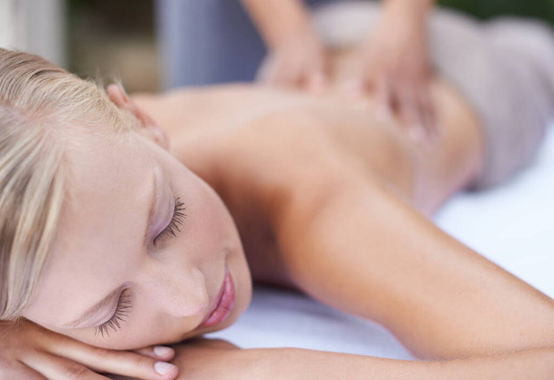 Treating herself to a day of luxury. A young woman getting a back massage at a spa - Foto, Bild