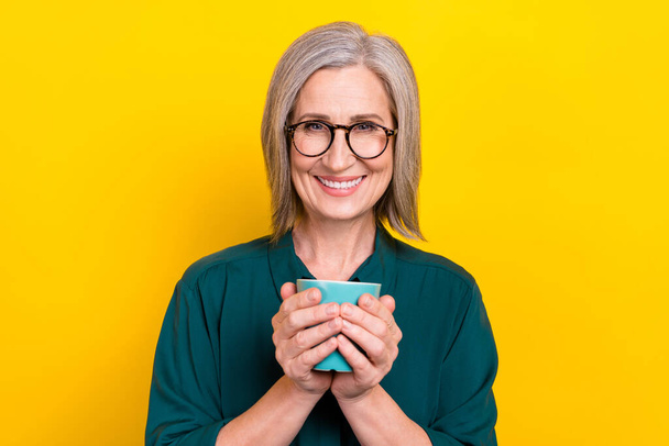Portrait of charming positive person beaming smile hands hold coffee cup isolated on yellow color background. - Foto, Bild