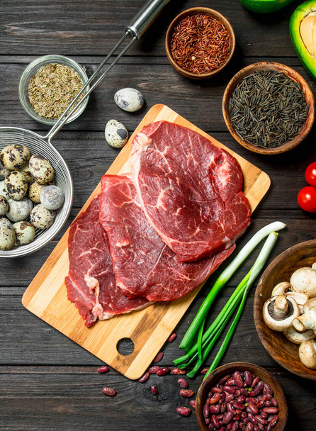 Healthy food. Raw beef with a variety of organic food and spices. On a wooden background. - Photo, Image