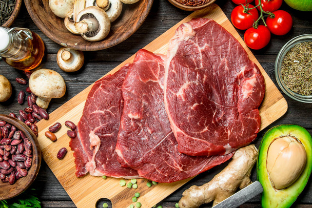 Healthy food. Raw beef with a variety of organic food and spices. On a wooden background. - Foto, Imagem