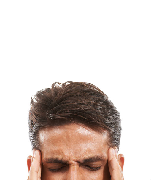 He has a hefty headache. Cropped image of a man frowning and pressing his temples in pain with eyes closed against a white background - Foto, immagini