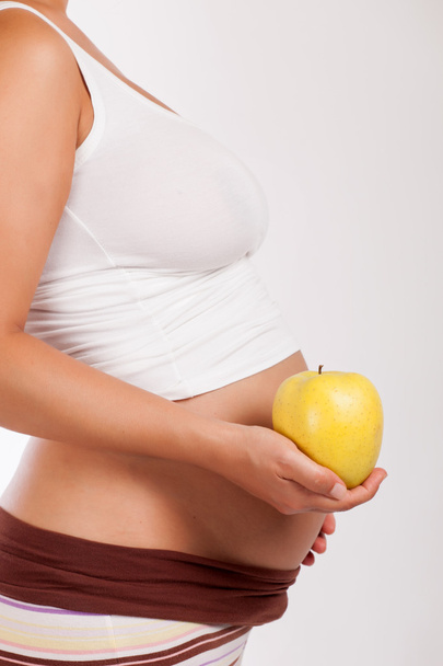 беременная женщина держит яблоко
 - Фото, изображение