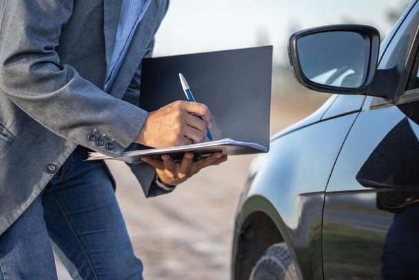 Insurance agent inspecting a car and taking notes. - Foto, imagen