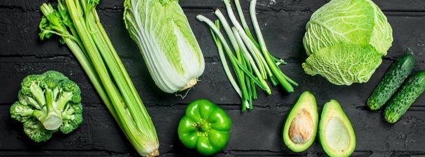 Organic food. Assortment of green healthy vegetables. On a black rustic background. - Photo, image