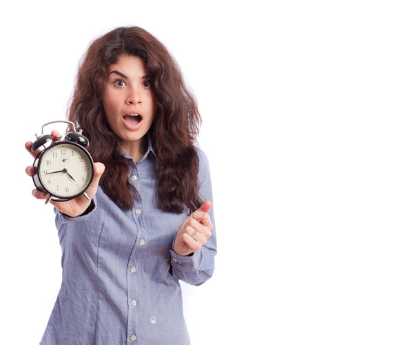 Astonished girl holding an alarm clock - Foto, afbeelding
