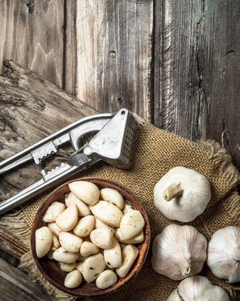 Garlic on a cutting Board with a garlic press. On wooden background - Foto, immagini