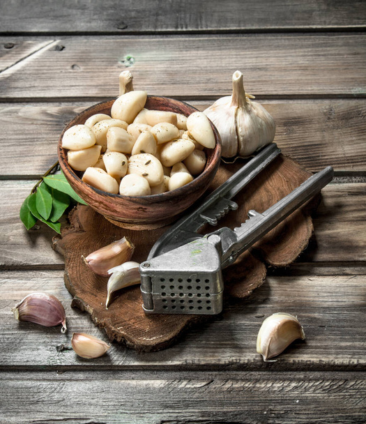 Cloves of fresh garlic on a cutting Board with a garlic press. On wooden background - Foto, immagini