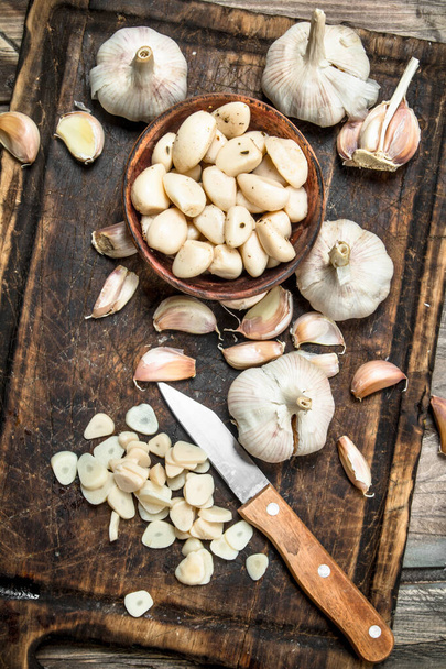 Garlic cloves on a cutting Board with a knife. On wooden background - Foto, immagini