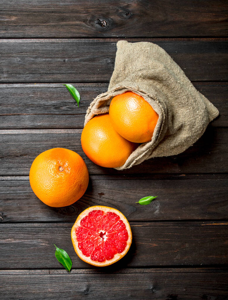 Grapefruits in an sack. On black wooden background - Foto, immagini