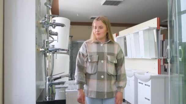 Een Amerikaanse vrouw kiest sanitair voor haar badkamer. Appartement renovatie concept. 4k video - Video