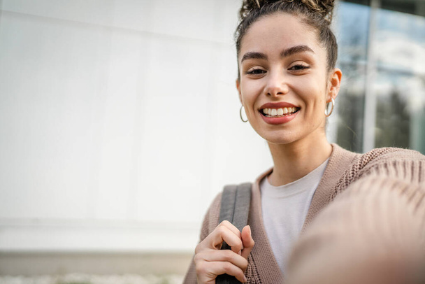 Uma mulher jovem adulto caucasiano fêmea stand ao ar livre posando auto retrato selfie feliz sorriso confiante no dia ensolarado - Foto, Imagem