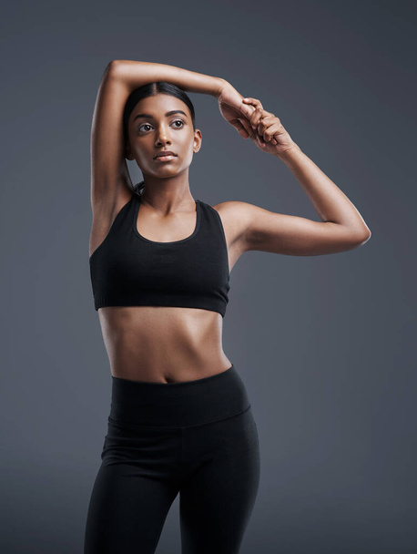 Idea, mockup and stretching with an athlete woman in studio on a gray background for fitness or health. Exercise, thinking and warm up with an attractive young female model training her body. - 写真・画像