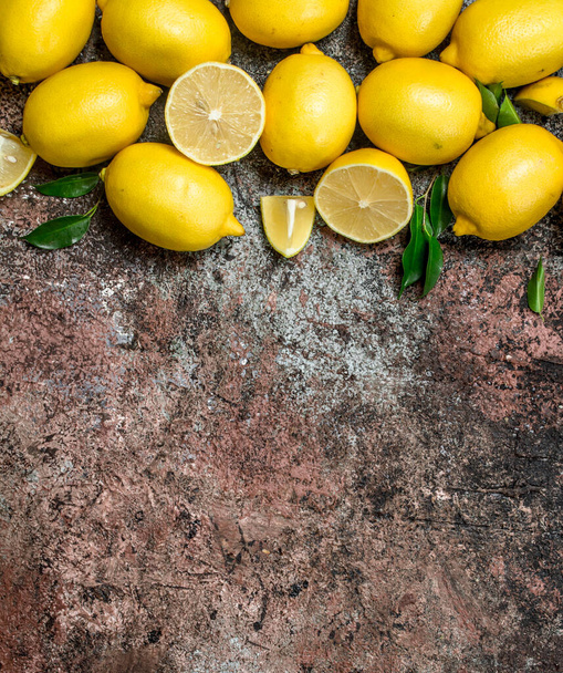 Fragrant fresh lemons with leaves. On rustic background - Valokuva, kuva