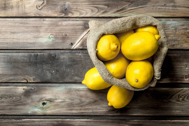 Fresh lemons in the sack. On wooden background - Photo, image