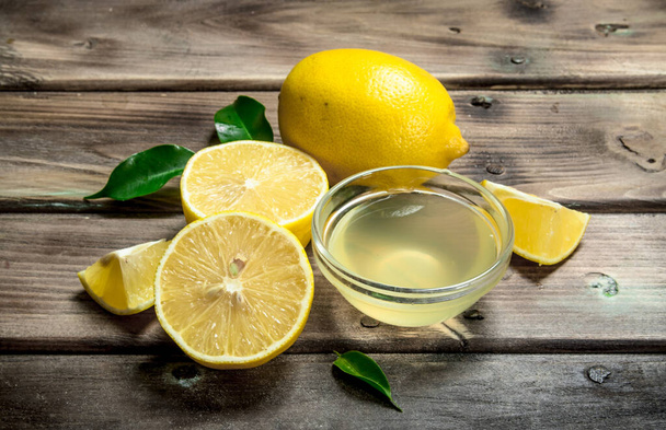 Lemon juice in the bowl. On wooden background - Photo, Image