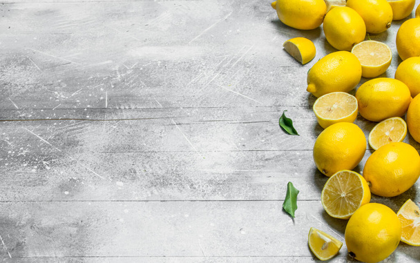 Juicy yellow lemons with leaves. On rustic background - 写真・画像
