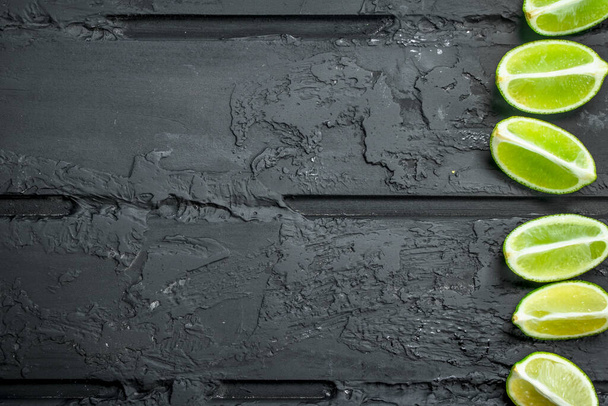 Slices of fresh juicy lime. On black rustic background - Foto, afbeelding