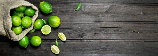 Fresh juicy lime in the sack. On wooden background - Photo, image