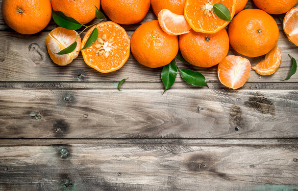 Halves and whole mandarins. On wooden background - Foto, Imagen