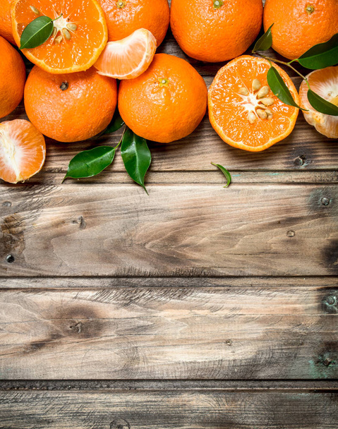 Halves and whole mandarins. On wooden background - Фото, изображение