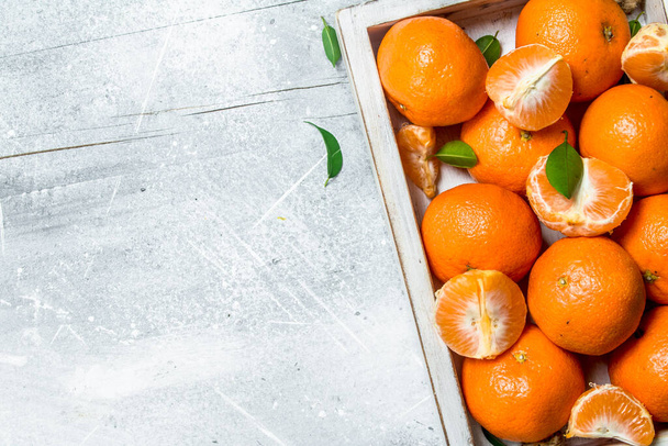 Fresh mandarins in the tray. On rustic background - 写真・画像