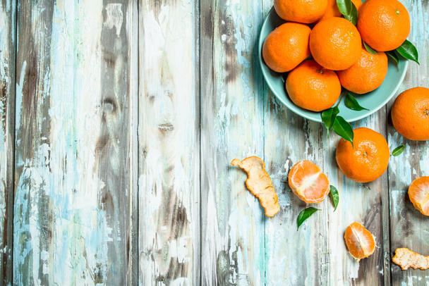 Mandarins in bowl and zest. On wooden background - Photo, Image
