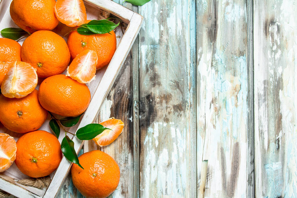 Fresh ripe mandarins with leaves in tray. On wooden background - Photo, Image