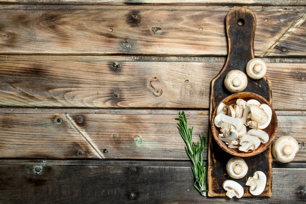 Pieces of fragrant mushrooms in bowl on cutting Board. On wooden background - Фото, зображення