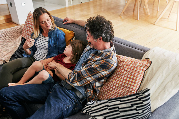 Mama, Papa und Kind entspannen sich auf der Couch im Wohnzimmer für Liebe, Fürsorge und gute gemeinsame Zeit in einem glücklichen Familienhaus. Junge, Kind und liebende Eltern in der Lounge für Unterstützung, Bindung und Glück auf dem Sofa. - Foto, Bild