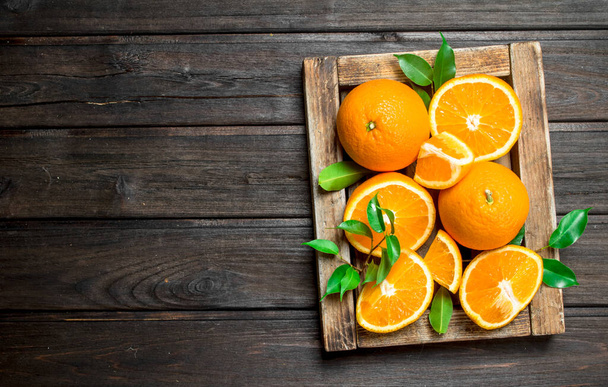 Cut oranges in tray. On wooden background - 写真・画像