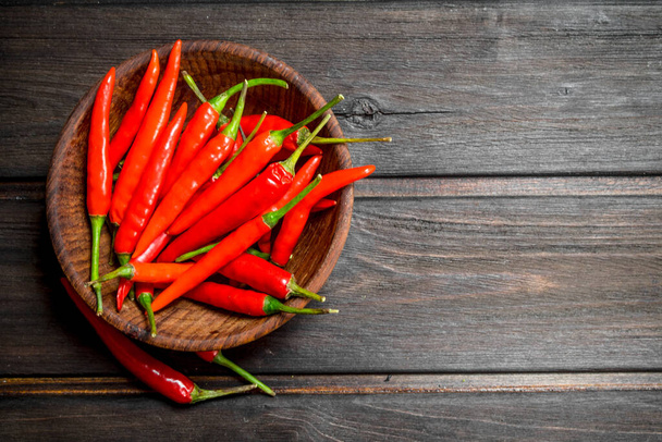 Red hot pepper in bowl. On wooden background - 写真・画像