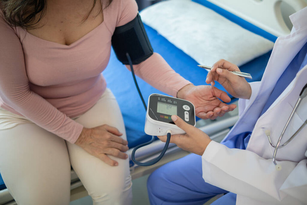 El médico está usando un monitor de presión arterial en un paciente de edad avanzada para comprobar si la presión arterial es anormalmente alta o no porque la hipertensión a menudo le sucede a los ancianos y es peligrosa. - Foto, Imagen