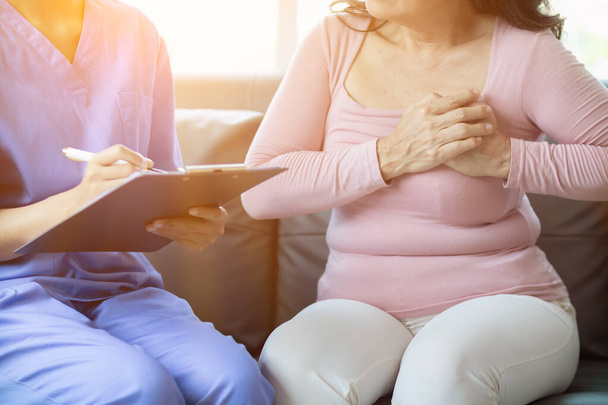 Eine ältere Frau lässt sich wegen Brustschmerzen beim Kardiologen untersuchen, weil sie eine Herzerkrankung vermutet. Suchen Sie einen Arzt auf, um sich untersuchen zu lassen und Ratschläge zur Behandlung zu erhalten. Gesundheitsuntersuchungskonzept zur Vorbeugung von Herzkrankheiten - Foto, Bild
