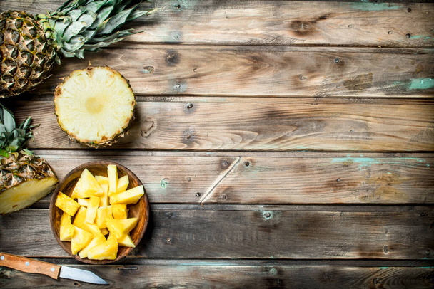 Pieces of ripe pineapple in a bowl. On wooden background - Φωτογραφία, εικόνα