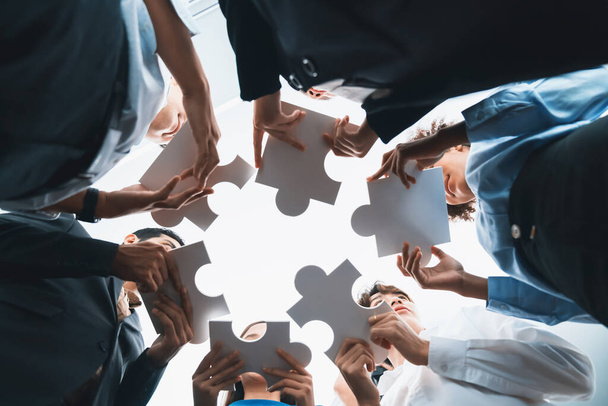 Hieronder een overzicht van diverse corporate officer medewerkers werken samen in kantoor verbinden puzzelstukjes als partnerschap en teamwork concept. Eenheid en synergie in business idee door het samenvoegen van legpuzzel. Koord - Foto, afbeelding