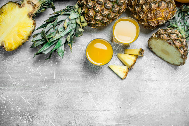 Fresh pineapple juice and ripe pineapples. On rustic background - Foto, immagini
