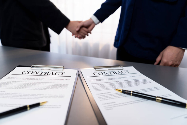 Focus closeup panorama business contract paper with pen, while two professionals shake hand in blurred background, signifying successful negotiation and partnership agreement with handshaking. Prodigy - Valokuva, kuva