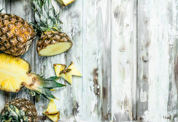 Cut and whole pineapple fragrant foliage. On wooden background - Foto, afbeelding