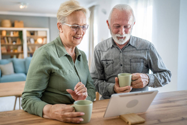 Ηλικιωμένο ζευγάρι καυκάσιος γέρος και γυναίκα σύζυγος και γυναίκα συνταξιούχος παππούς και η γιαγιά χρησιμοποιούν ψηφιακή ταμπλέτα για online βιντεοκλήση στο σπίτι σε φωτεινό δωμάτιο πραγματικοί άνθρωποι έννοια οικογένεια αντίγραφο χώρο - Φωτογραφία, εικόνα