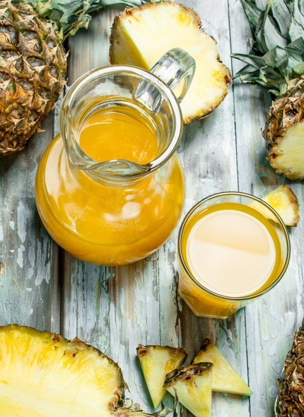 Pineapple juice in a glass and jug. On wooden background - Foto, immagini