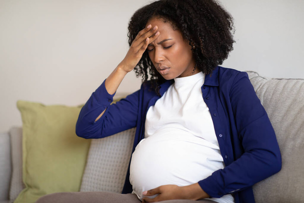 Unzufriedene Millennial American schwangere Dame mit dickem Bauch leiden unter Kopfschmerzen und Gesundheitsproblemen. Migräne, Babyerwartung, Mutterschaft und Stress, Druck, Depression, Krankheit - Foto, Bild