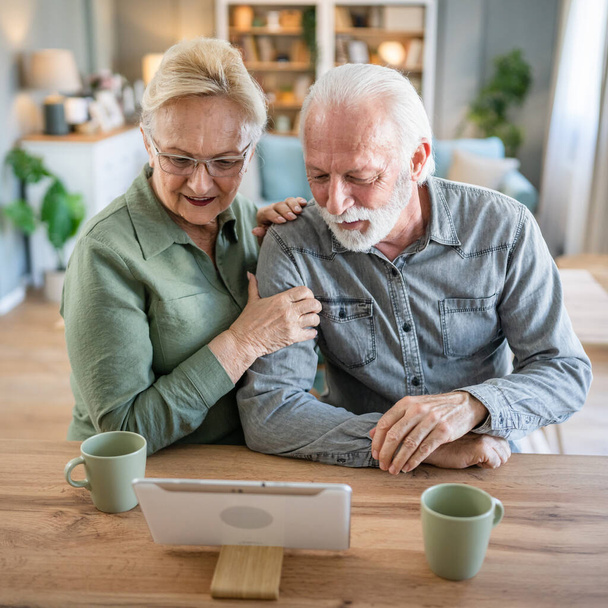 Senior couple caucasian old man and woman husband and wife pensioner grandfather and grandmother use digital tablet for online video call at home in bright room real people family concept copy space - Foto, Bild