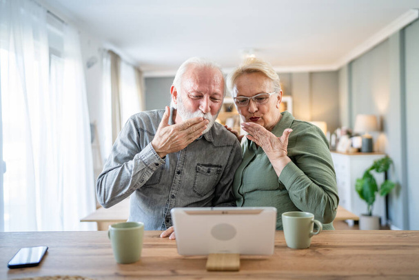 Senior couple caucasian old man and woman husband and wife pensioner grandfather and grandmother use digital tablet for online video call at home in bright room real people family concept copy space - Photo, Image