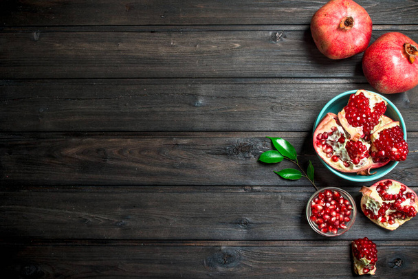 Grains of ripe pomegranate in bowl. On wooden background - Foto, Imagen