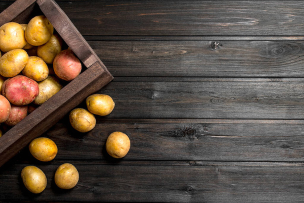 Fresh potatoes in a wooden box. On wooden background - Foto, immagini
