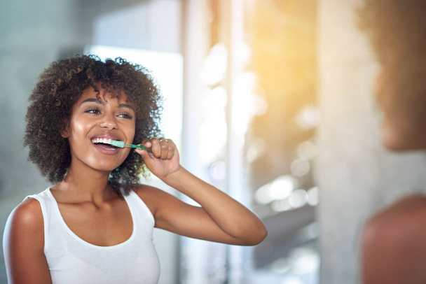 Mirror, dental and black woman brushing teeth, fresh breath and oral health in the bathroom. Female person, happy model and lady with wellness, mirror and hygiene with morning routine and tooth care. - Fotografie, Obrázek