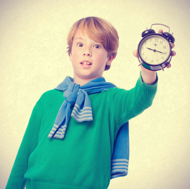Child holding an alarm clock and concerned about the time - Photo, Image