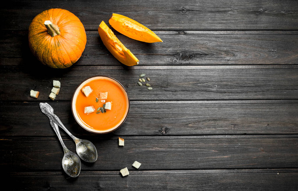 Pumpkin soup in bowl with rusks and spoons. On wooden background - Foto, Imagen